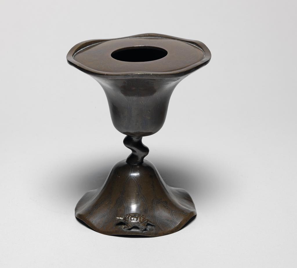 An image of Bronze candlestick, inlaid with silver, in the shape of a lotus leaf with a wavy edge. possibly Korean. 1600-1799.