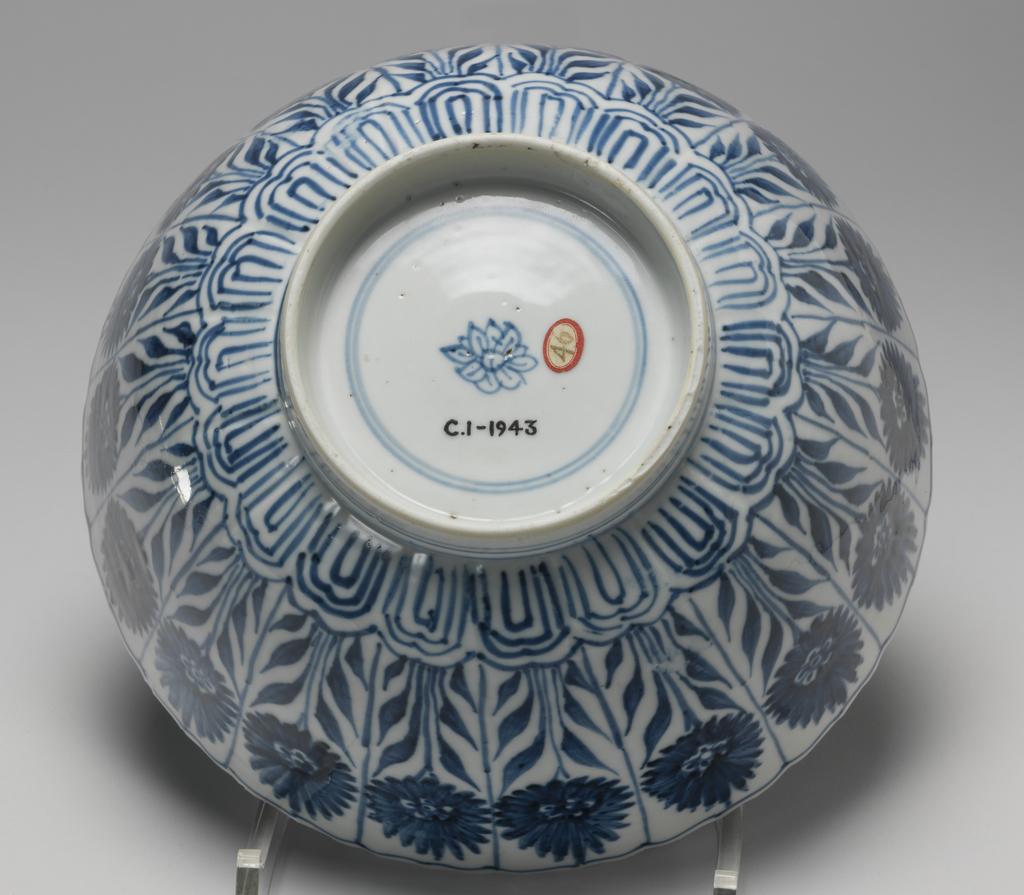An image of Bowl. With an aster pattern in panels outside, and three in a central panel amid scrolls inside. Slightly lobed. Mark like a flower in blue, within two concentric circles. Hard-paste porcelain, height 9.5 cm, diameter 20.9 cm. Kangxi Period (1662-1722). Chinese.