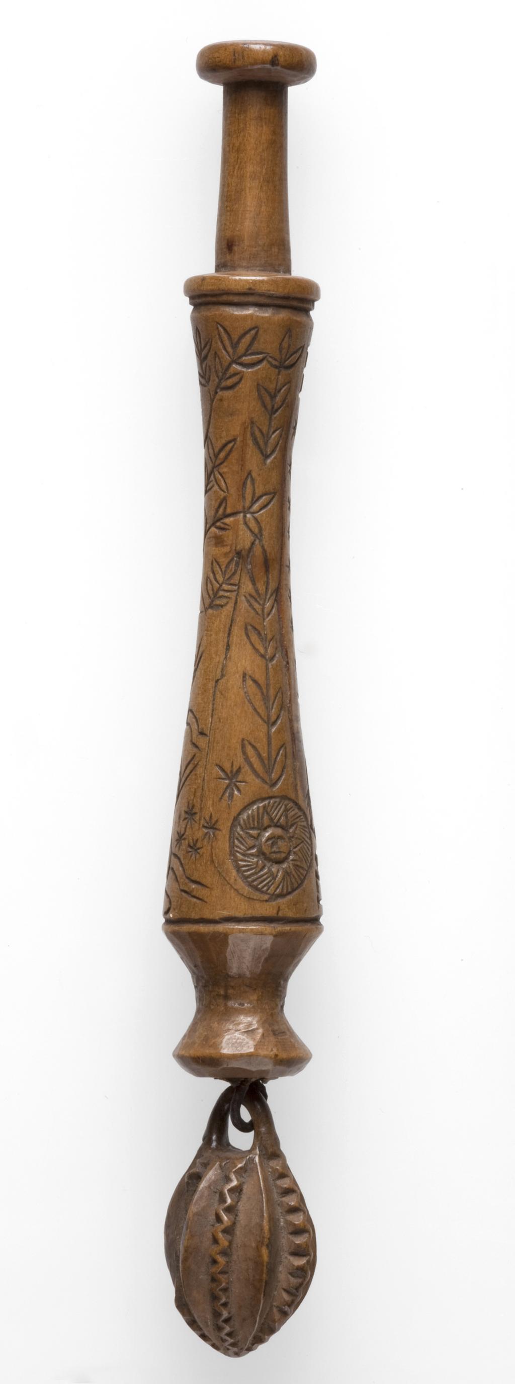 An image of Lace Bobbin. Unknown maker, Bedfordshire, Dunstable Downs. Wood, carved with figures (maker and his wife), sheep, (his) dog, bushes and the sun, moon and stars. Circa 1795. No dimensions.