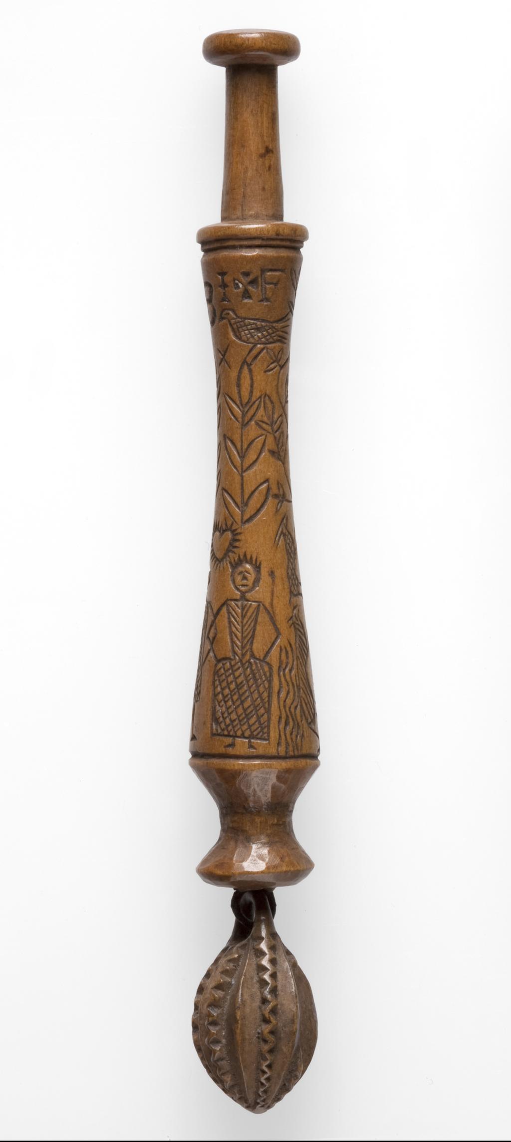 An image of Lace Bobbin. Unknown maker, Bedfordshire, Dunstable Downs. Wood, carved with figures (maker and his wife), sheep, (his) dog, bushes and the sun, moon and stars. Circa 1795. No dimensions.