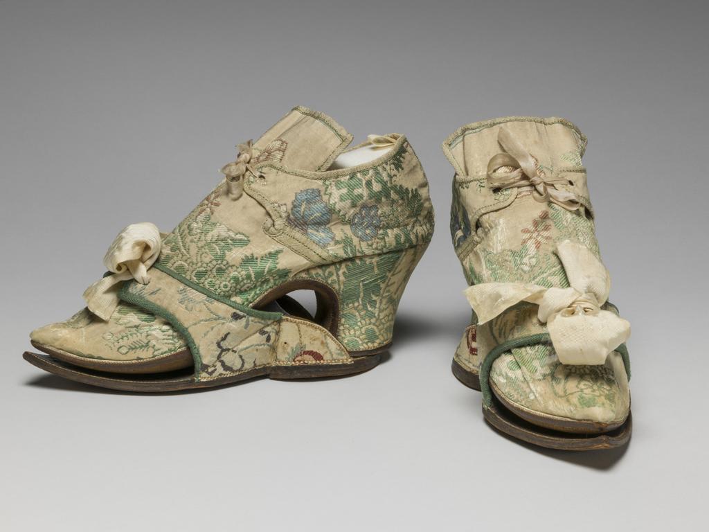 An image of Textiles/Shoes and pattens. Brocaded silk, cream background, multicoloured floral design. Shoes lined with coarse linen, tongues with green sarcenet, bound green braid. Pattens lined scarlet flannel, bound green braid, cream corded silk bows, leather soles and heels. Length, whole, 8.25 in, circa 1700-1749. English.