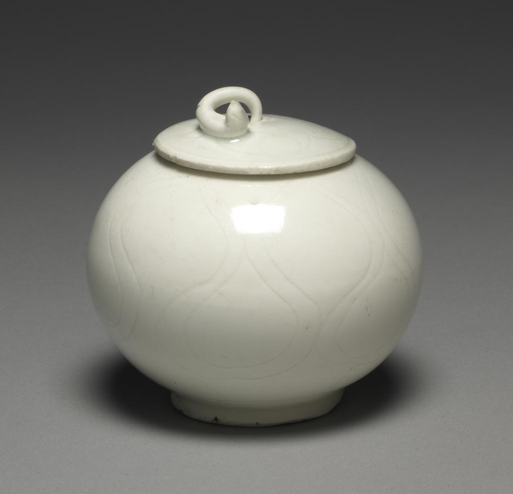 An image of Box and cover. Hard-paste porcelain with incised decoration underglaze, height, whole, 8.0 cm, diameter, whole, 8.3 cm. Chinese. Made for Arab or Indonesian market?