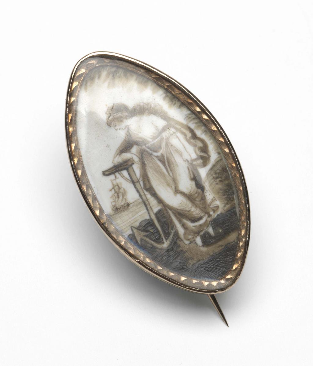 An image of Jewellery. Mourning Brooch or Pendant. Unknown maker, England. Marquise-shape, containing, under glass, a scene, in sepia, of Hope leaning on an anchor; in the background a ship at sea. Surrounding the scene, under the glass is a chased border. On the reverse is inscribed the script monogram of the initials 'EB'. Gold and ivory, height, whole, 4.5 mm, depth, whole, 22.0 mm, length, whole, 37.5  mm. Neoclassical. Spencer George Perceval Collection.