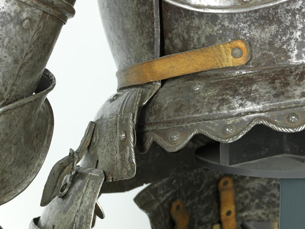 An image of Armour/half armour. Unknown production, Germany. Half armour consisting of a burgonet, an 'Almain' collar, a cuirass, a pair of short tassets, and two pauldrons and vambraces, nearly forming a pair. Most of the armour originally had a 'black from the hammer' finish, now cleaned to a mottled bright finish with medium to heavy pitting overall. Steel, hammered, riveted. Circa 1550-1610. Notes: all within these dates apart from the pair of short tassets, which have been partly reworked and formed of 16th century plates in the 19th century. Provenance: From the armoury of the Princes Radziwill, Castle of Niescwiez, Poland. Parts: HEN.M.1C-1933HEN.M.1B-1933HEN.M.1A-1933HEN.M.1D-1933HEN.M.1E-1933