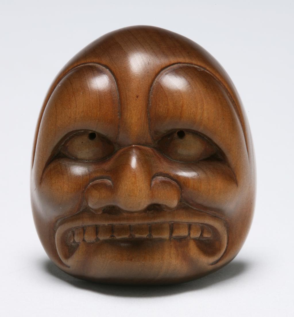 An image of Netsuke. A Buaku mask. Unknown maker, Japan. Wood, carved, 1800-1900.