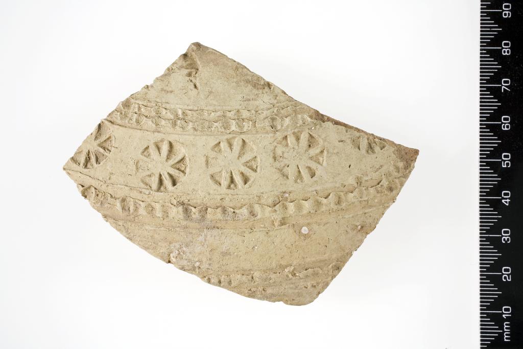 An image of Vessel/Sherd. Fragment, from closed vessel, with impressed decoration of double cable and cartwheels. Production and Find Spot: Tell Kuyunjik (Nineveh), Iraq. Pink clay, grit temper, length 0.072 m, width 0.093 m.
