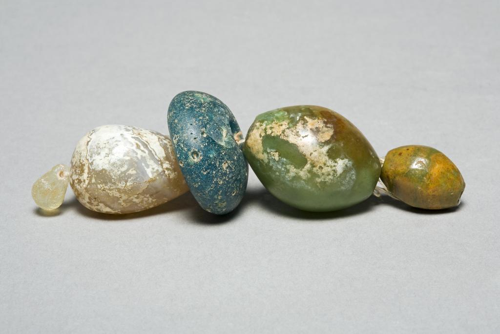 An image of Jewellery/Beads (4). Find Spot: tombs Aleppo, Israel. Light blue glass and chalcedony. Persian-Roman period.