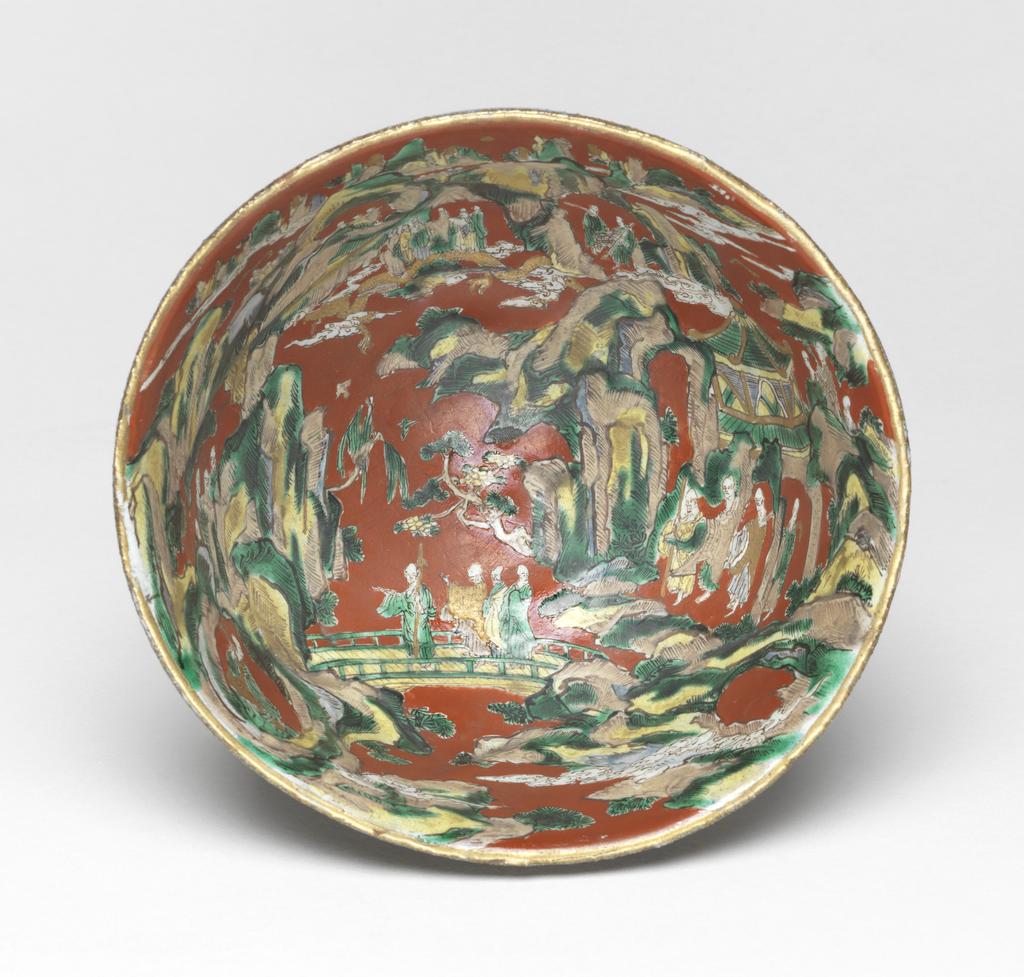 An image of Japanese pottery. Bowl. Aoki, Mokubei (Japanese, 1767-1833). Footed rough stoneware bowl, thrown and turned, with everted rim. The outside is plain with matt glaze of brown/yellow colour. The inside is highly decorated in enamels on a red background, with heavenly mountainous landscape, in which are many scholars, a bridge, dragon, pavilion, etc. Stoneware, thrown and turned, exterior with matt glaze of brown/yellow, interior brush painted green, yellow, brown and white, height, whole, 9.90 cm, diameter, rim, 16.00 cm, largest, diameter, foot, 6.20 cm, circa 1775 to circa 1825. Edo Period (1615-1868). Production Place: Japan, Kyoto.