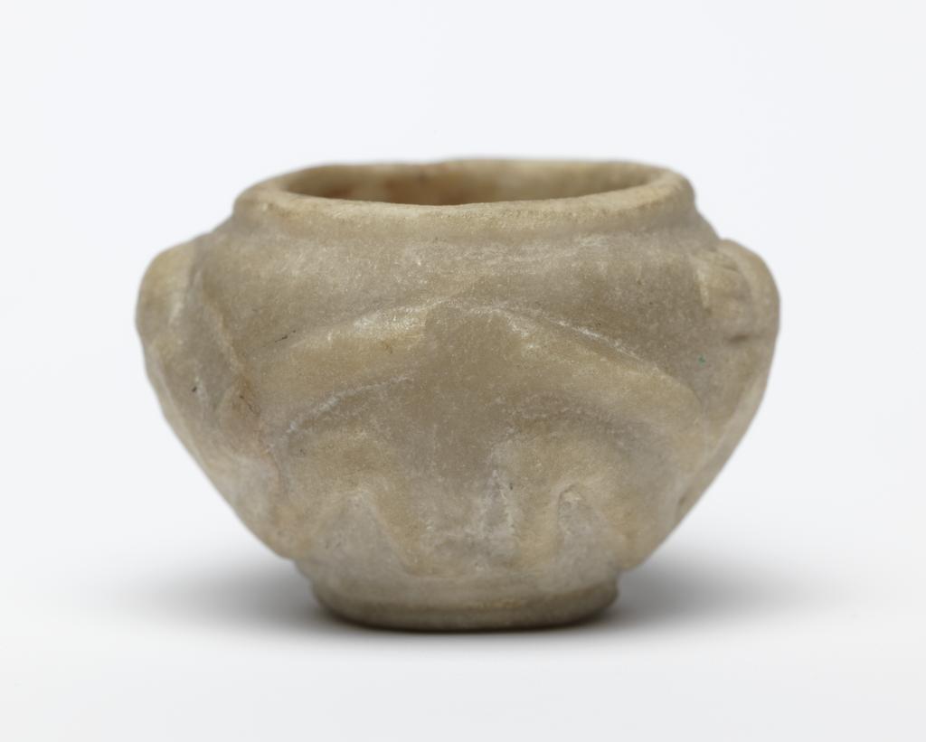 An image of Stone vessel. Calcite vessel with monkeys. Jar, squat, with two monkeys on outside in relief. Used as an eye-paint jar. Production Place/Find Spot:: Egypt. Calcite, carved, height 2.2 cm, 1976-1794 B.C. Dynasty 12.