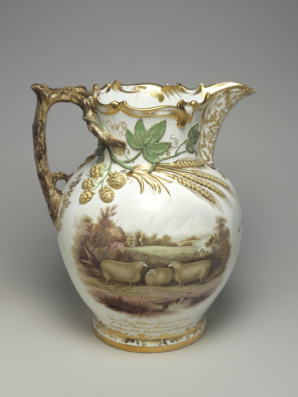 An image of Jug/Ale Jug. Commemorative Jug. Coalport Porcelain Factory, Shropshire. Feltspar. The bulbous body has a projecting base, a cylindrical neck with relief scrolls around the rim, an upward curving lip, and an angular branch handle which divides into two at the top and has a lateral twig on the left of the lower end. Both sides of the neck and shoulder are decorated with sprays of applied hops and barley extending from the upper ends of the handle towards the lip. One side of the body is painted with a view of a massive ox standing facing to the right in a landscape, with below in gold, 'Earl Spencers Prize Durham Ox/exhibited at the Smithfield Club Show/Xmas 1843'. On the other side there are three wethers (castrated male sheep), one facing front and two facing inwards on either side of it, standing in a landscape with below in gold 'Three Prize Wethers Bred & Fed by/Mr Richd. Hickson of Hougham near/Grantham which attained 4 first Prizes in 1837'. Below the lip there is a group of agricultural implements comprising a sickle, scythe, rake, pitchfork, plough and harrow ?, and below the handle, a stook of corn. The base and the lower end of the handle are encircled by wreaths of oak leaves and acorns, and there is a formal leaf design under the lip. The scrolls on the rim are gilded and there is a broad gold band round the edge of the base. Soft-paste porcelain, moulded in two halves, with applied moulded reliefs, applied moulded handle, and feldspathic glaze, painted overglaze in enamels and gilded. Height, whole, 46.3 cm, height, whole, 45.7 cm, width, whole, 38 cm, circa 1844. Rococo Revival. Circular pink 'gold medal' mark. Notes: The term 'feltspar porcelain' in the mark on the base of the jug refers to the lead-free glaze for which John Rose & Co. won a Society of Arts Gold Medal on 30 May 1820, rather than to the body of the ware, which was a soft-paste porcelain.