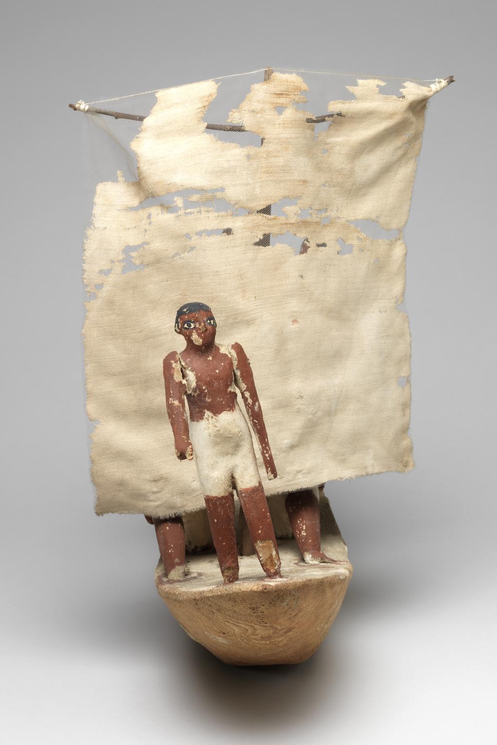 An image of Wooden model of a sailing boat, with two men pushing at the boat using a pole; three men hoisting the sail; one man operating the rudder, and one look out on the prow. Boat painted yellow, men have white kilts, black hair and red-brown bodies. Plaster coating in some places. Production Place: Egypt. Find Spot: Beni Hasan; tomb 366 (Khety). Wood, plaster and linen, painted, height 40.5 cm, length 62 cm, circa 2010- circa 1950 B.C. Early dynasty XII, Twelfth Dynasty; Middle Kingdom.