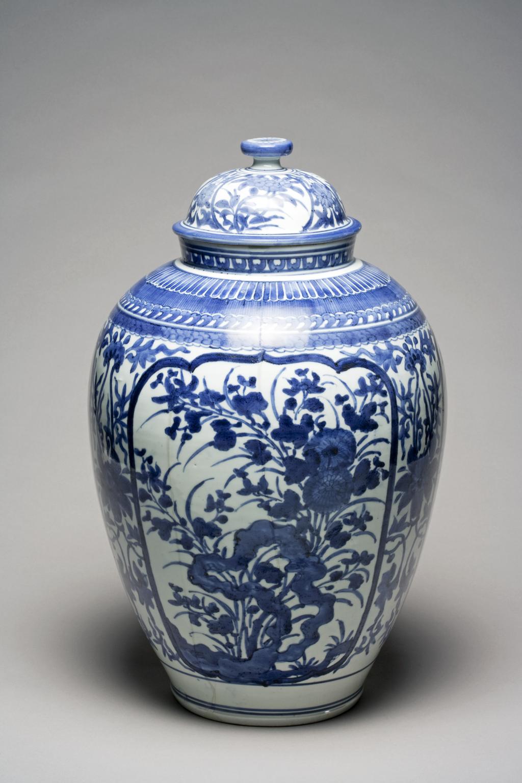 An image of Jar and cover with panels of flowers of the four Seasons.  Hard-paste porcelain painted underglaze in blue, height 48.5cm, width 28cm, circa 1660-1670. Japanese.