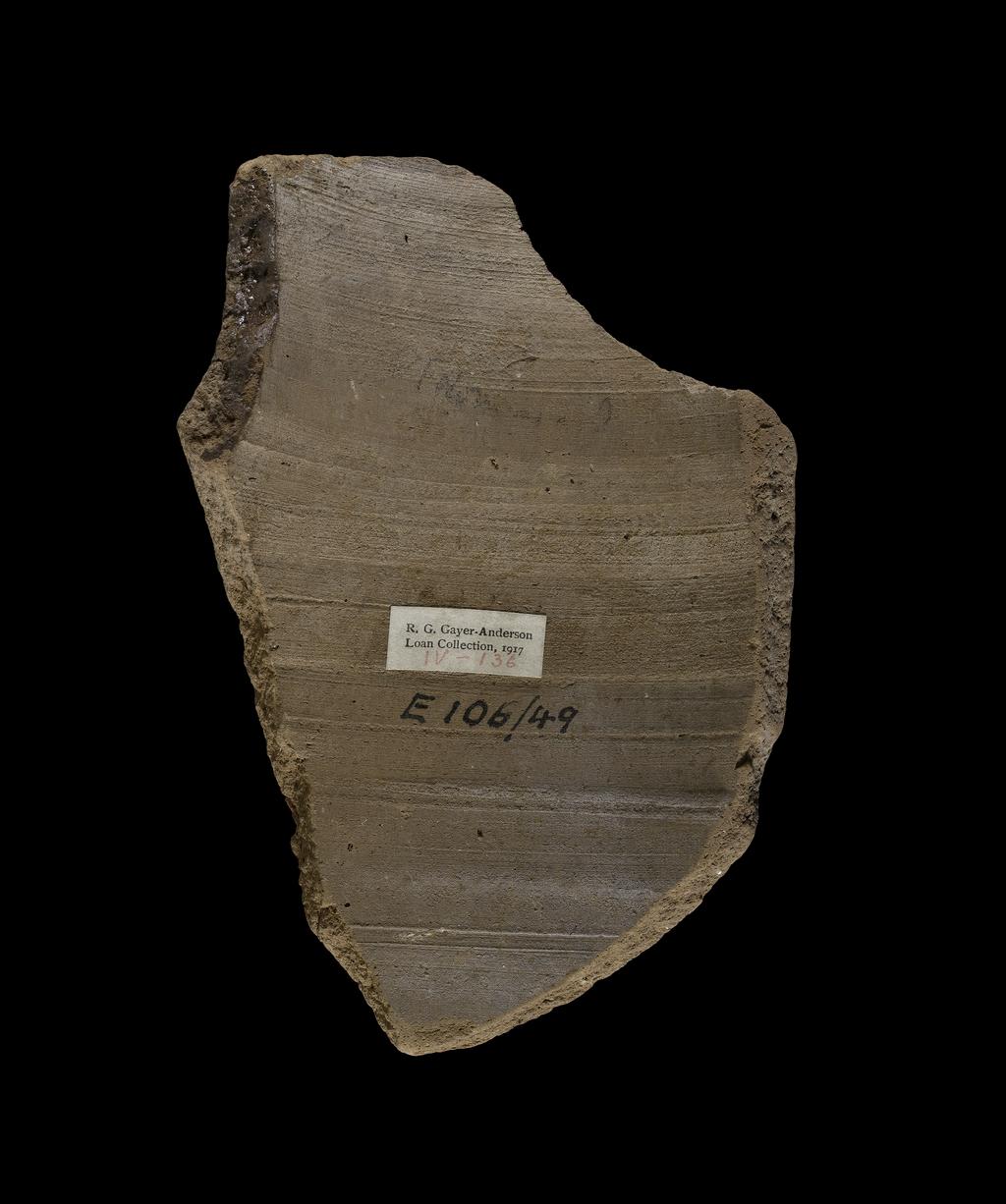 An image of Written Document. Ostracon, Figured. Clay, ceramic, diameter 9.8 cm, height 13.9 cm. Fragment of a Jar with decoration in black paint of an unkempt man carrying bags on a stick, possibly a yoke. Egypt, New Kingdom. Circa 1550-1069 B.C.