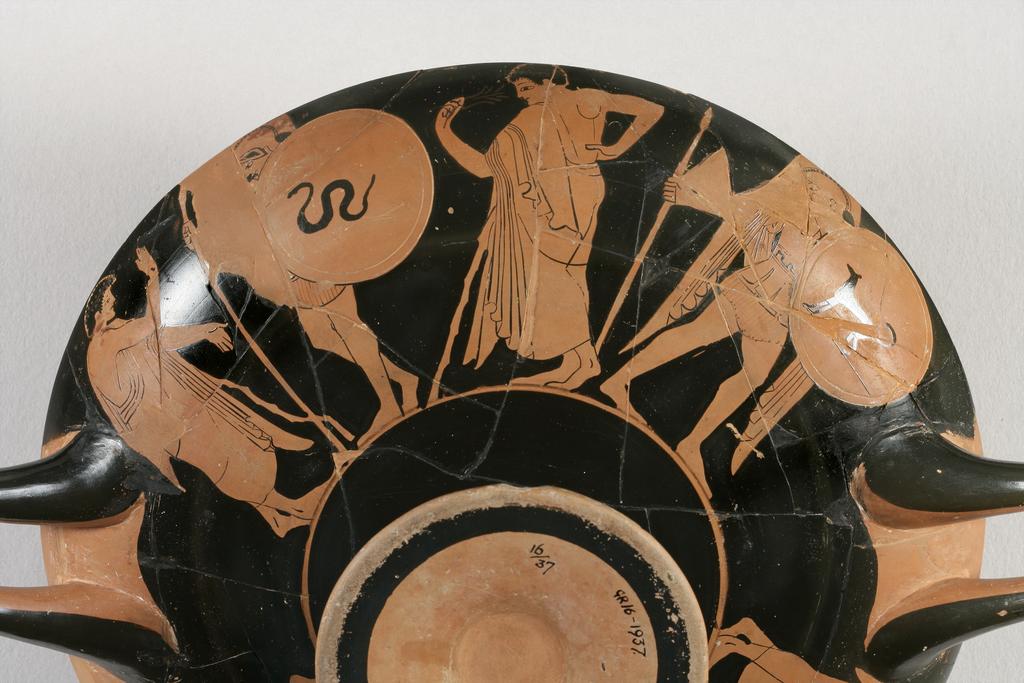 An image of Vessel/Cup. Painter of Berlin 2268 (vase-painter, ca. 530-500 BC). (A,B) warriors and draped youths, one with flower, snake, dog, tripod (I) draped man with staff. Production Place: Athens. Find Spot: Vulci Etruria Italy. Red figured, clay, diameter, 0.273 m, height 0.106 m, width 0.351 m, diameter, 0.146 m. 500-490 B.C. Archaic Period.