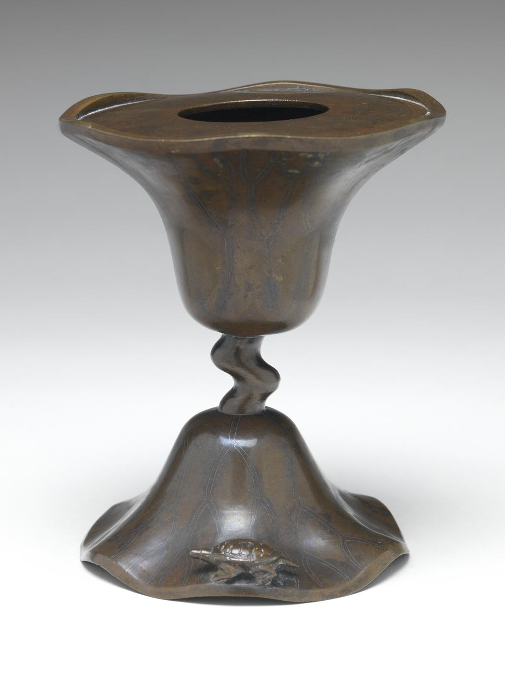An image of Bronze candlestick, inlaid with silver, in the shape of a lotus leaf with a wavy edge. possibly Korean. 1600-1799.