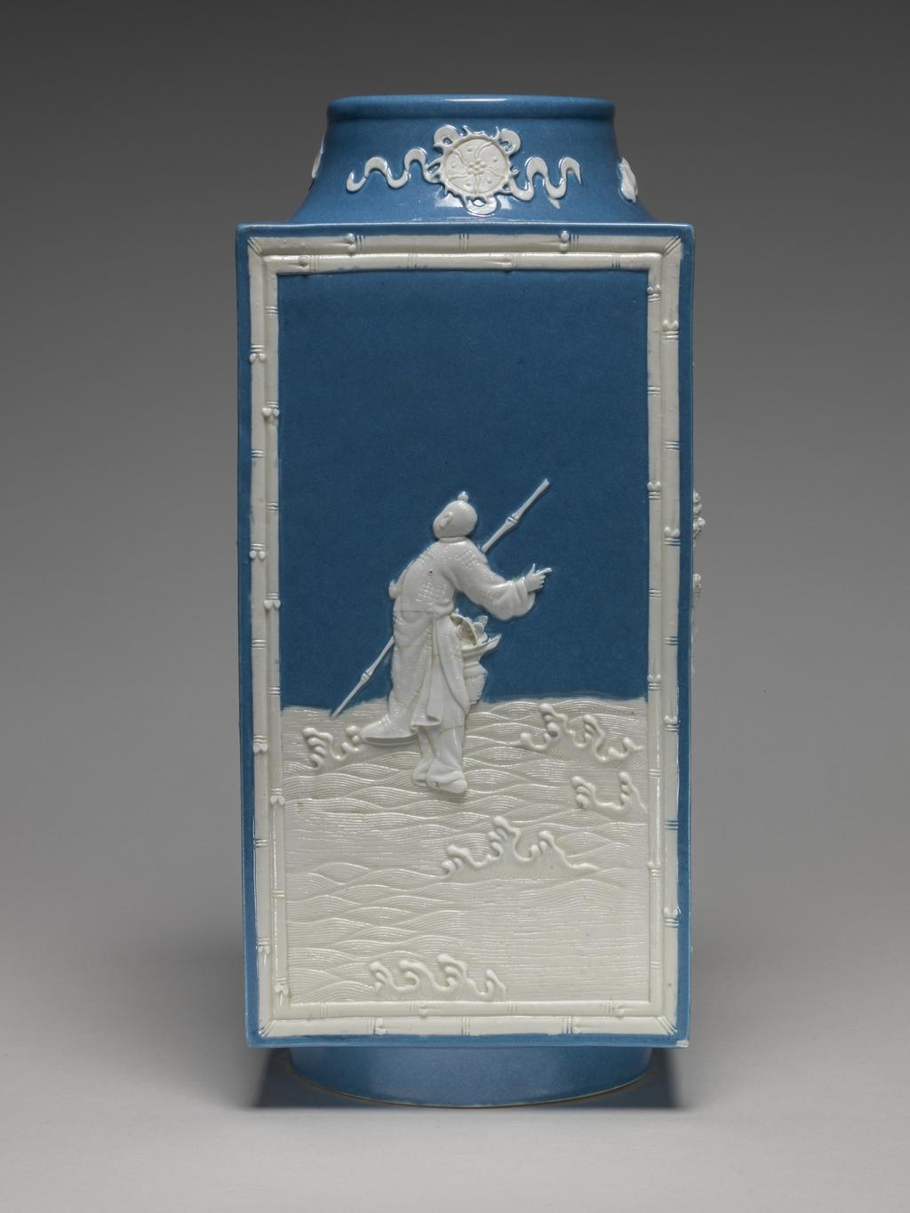 An image of Vase. One of two square stoneware vases, with a sloping cylindrical neck and cylindrical foot ring. With applied white reliefs and opaque powder blue glaze on the interior and parts of the exterior. Decorated on the sides with four of the Eight Immortals standing on waves, enclosed by a rectangular bamboo border, and on the neck with four symbols, all in white. The immortals are Lu Dong-bin (with sword), Li Tie-guai (with crutch and gourd), Lan Cai-he (with basket of flowers) and Zhang Guo-lao (with rods in cane). Mark: Six character seal script mark of Qianlong. Stoneware, powder blue glaze, with applied relief, height 28.5 cm, width 12.5 cm. Qianlong Period (1736-1795). Chinese.