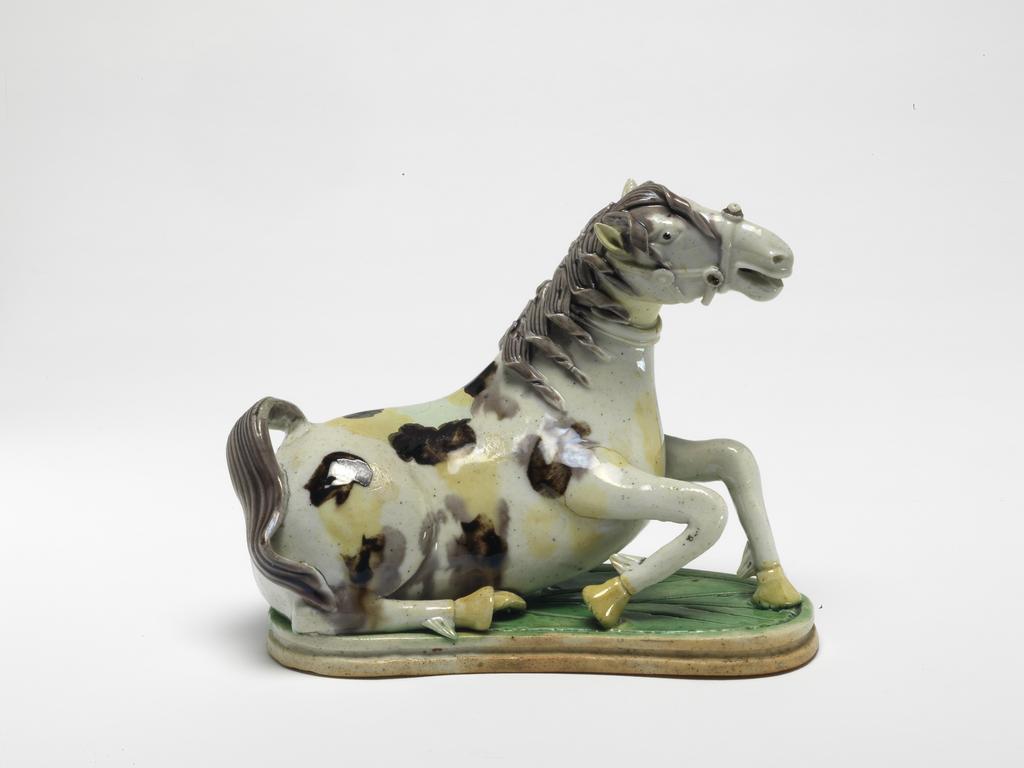 An image of Animal figure. Horse (one of a pair). Unknown maker, China. With brown and yellow splodges, on a green stand. In the act of rising. Hard-paste porcelain, length, 14.6, Kangxi Period (1662-1722). Chinese.