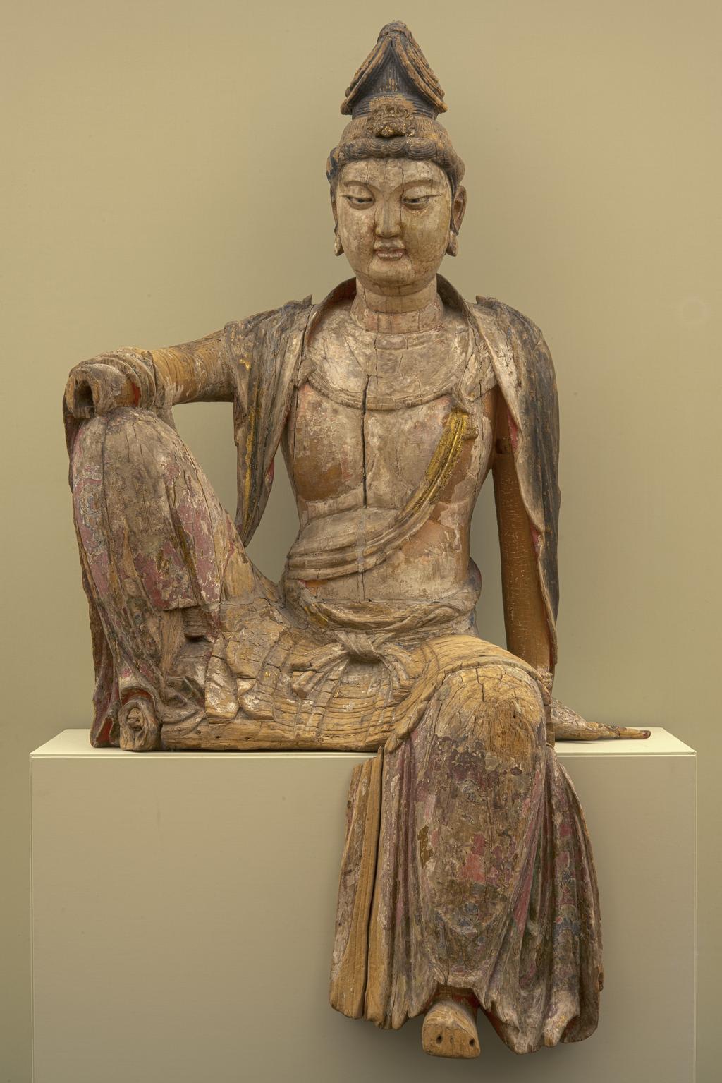 An image of Sculpture/figure. Seated Bodhisattva. Unknown sculptor, China. Lifesize polychrome wooden sculpture of a Bodhisattva seated in the position known as "royal ease". Several wooden elements are missing including the proper right hand and forearm, the proper right foot, the forepart of the proper left foot, the forepart of the proper left first finger and the front edge of the lower garment (centre to proper right). The sculpture has been decorated with several successive campaigns of polychromy (paint and gilding), now very fragmentary and abraded. The eyes are inlaid with polished glass or stones. Carved and filled wood contructed from several jointed elements (some possibly repairs); the eyes inlaid with polished cabochons, either glass or gemstones. Painted (over ground layers) in several campaigns of polychromy, at least one including gilding. 1200-1279. 13th century. Song Dynasty (AD 960-1279).