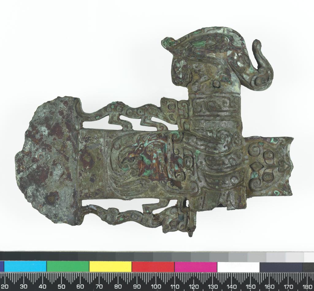 An image of Axe head. The blade, socket, and socket cap all one piece of metal. The blade is flanked by two tigers. On the blade is a coiled dragon, a conventionalised dragon's head, and a t'ao t'ieh mask in the piece of blade at the back. On the cap is an elephant's head with horse's legs and a tiger's head at the back. Bronze, height 11.1 cm, length 14.6 cm, circa 500-249 B.C. Chou dynasty (1122-249 BC). Chinese Warring States period.