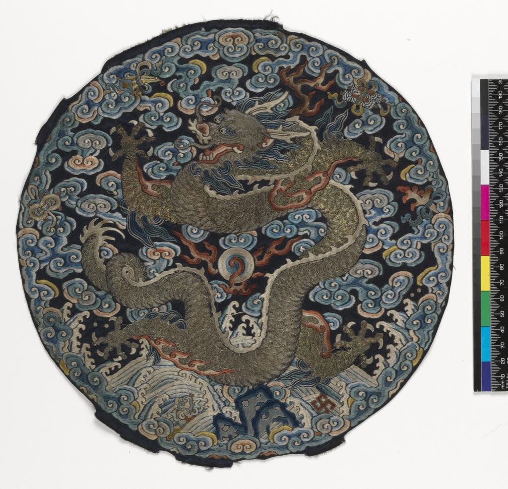 An image of Textiles. Roundel. Unknown maker, China. Five-clawed dragon on a background of waves and clouds, with six precious objects around perimeter. Silk and metal embroidery on satin; blue ground with polychrome embroidery - satin stitch, stem stitch, encroaching satin, seed stitch (Peking knot), with laid and couched work. Diameter, whole, 28 cm, circa 1750-circa 1775. Acquisition Credit: Given by Mrs. Soame Jenyns, in accordance with the wishes of her late husband, Soame Jenyns.
