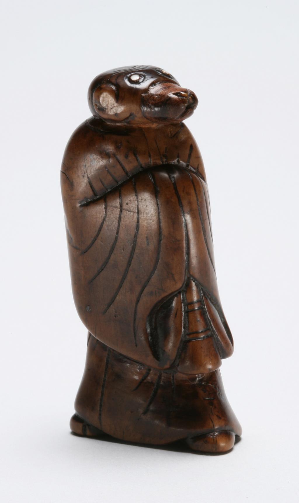 An image of Netsuke. A standing monkey dressed as a priest. Unknown maker, Japan. Boxwood, with inlaid ivory eyes, 1770-1800. 