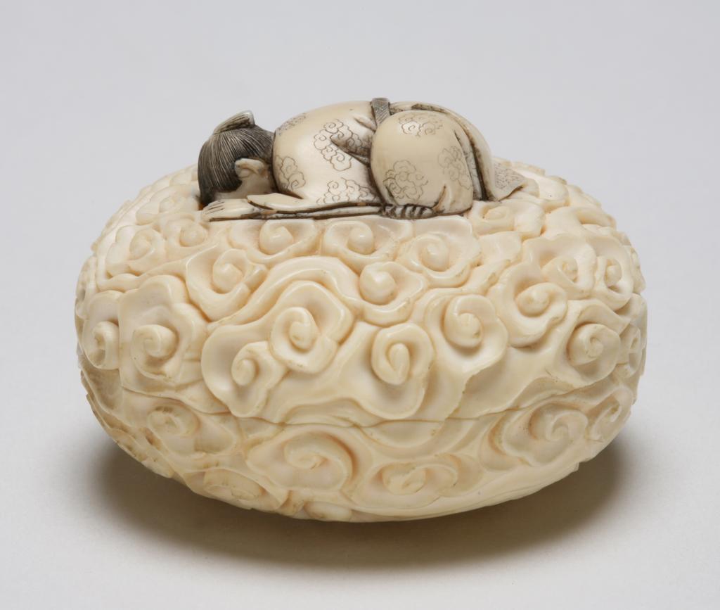 An image of Netsuke-Manju. Unknown maker, Japan. A man crouching and looking down on top of clouds, looking through the clouds to peep at a young lady bathing. This is a two piece Netsuke, the young lady inside. Ink detail at hair work. Ivory, carved, 1870-1930.