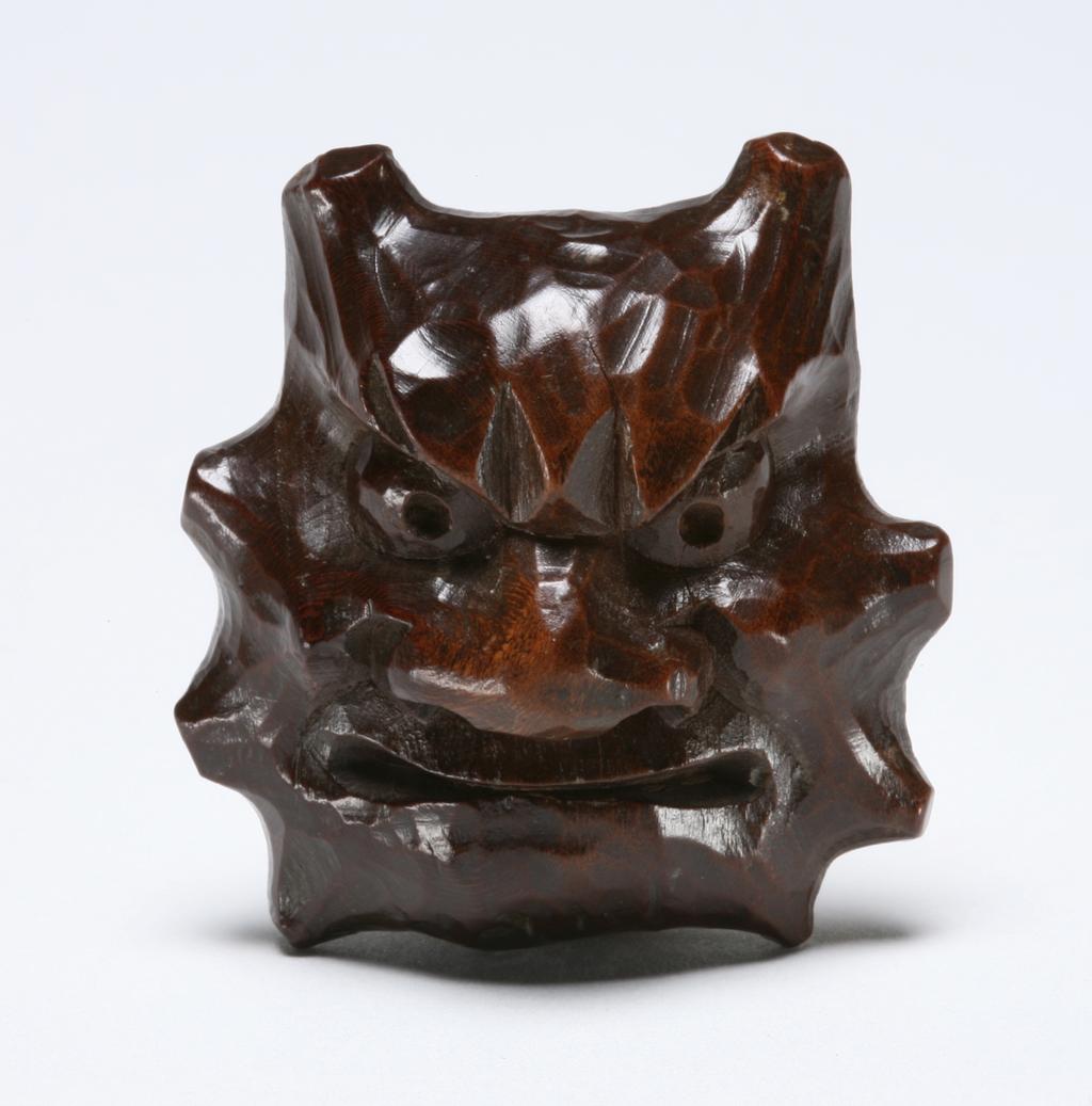 An image of Netsuke. Unknown maker, Japan. A mask of Oni (two-horned), an Okame mask on the reverse side. Boxwood, carved, 1800-1899.