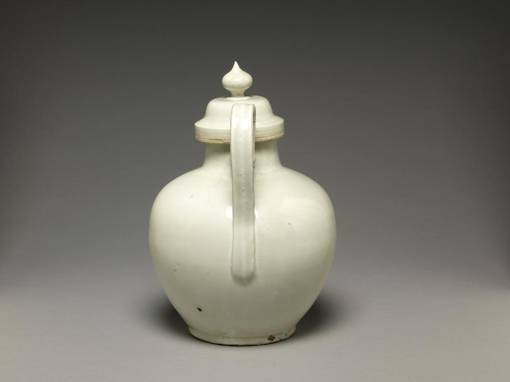An image of Ewer. Drinking vessel and cover. The handle is long, and the spout is short. Porcelain, white glaze, height 20.3 cm, length 14.3 cm, 1131-1162. Shao Hsing period. Song Dynasty (960-1279). Chinese.