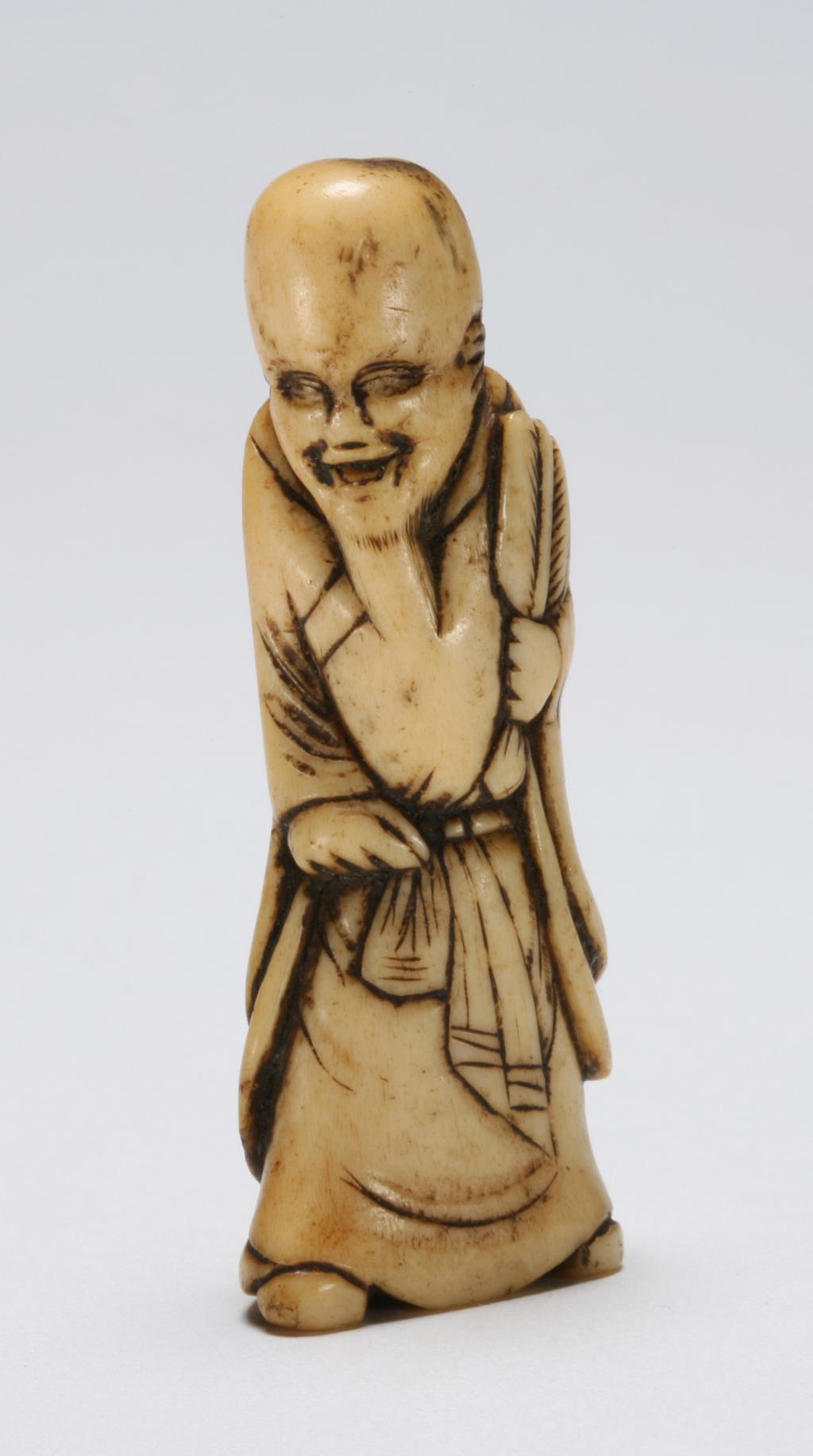 An image of Netsuke. Unknown maker, Japan. Fukurokuju standing with his fan in his left hand. Stag antler, 1770-1830.