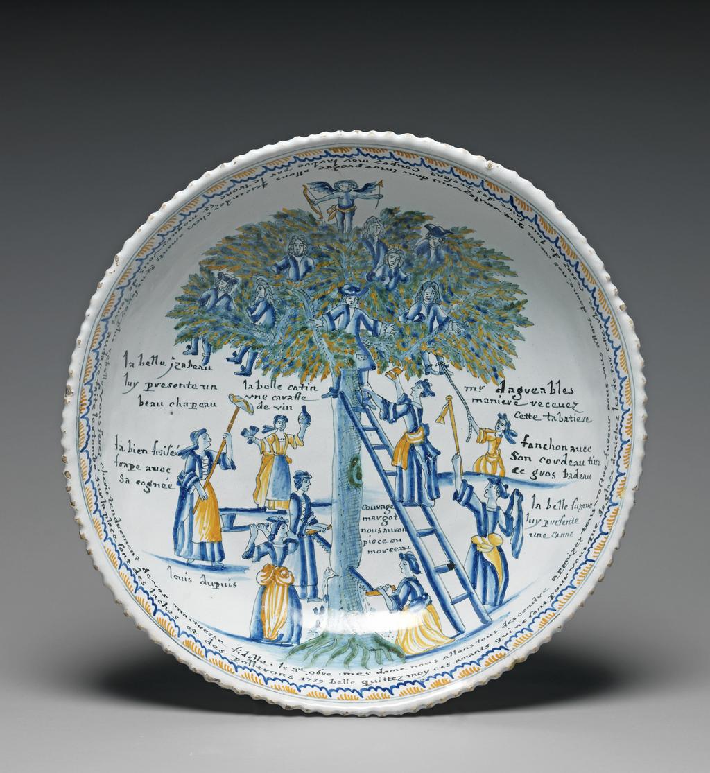 An image of Bowl. L'Arbre d'Amour. Unknown production, France, Nevers. Bowl (faïence) painted in polychrome with Cupid standing on a tree in which several men have taken refuge from a group of women who are trying to get them down. Circular with a crinkled edge, deep curved sides obliquely fluted, standing on a footring. Decorated with' L'Arbre d'Amour'. Cupid, holding a bow and arrow, stands on top of a tree in which seven men have taken refuge from a group of eight women who are trying to tempt them down. Two of the women are sawing down the tree, and to its right are the words, 'courage/margot/nous auron/piece ou/morceau'. A woman on the left holds up an axe and is captioned 'la bien frisé(?)/frape avec/sa cognée'.Another holds up a hat on pole, and is captioned, 'la belle Izabeau/luy presente un/beau chapeau', and below her is the name, 'louis dupuis'. Further back, a woman holds up a flask and is captioned 'la belle catin/une caraffe/de vin'. On the right a woman climbs up a ladder propped against the treetrunk to offer a box to a man in the tree, captioned on the extreme right 'Mr lagreables/ maniere recevez/cette tabatiere'. Another holds up a cane, and is captioned 'la belle Suzanne luy presente/une canne', and a third tries to drag a man from the tree by a rope, and is captioned 'fanchon avec/son cordeau tire/ce gros badeau'. Round the rim are two lines of inscription. The outer line reads: 'belle quittez moy ces amants qui ne sont pour vous que de glace denichez les de sur cette arbre cessez de leur faire des present coupez moy larbre par le tronc et moquez vous de leurs audace faite les tombe sur la place sont des laches et des poltrons'. The inner line reads: 'mes dame nous allons tous descendre Appaizez tous vostre furerur nous vous allons donn nos coeurs que voulez vous donc entre pre(n)dre allons descendez chers amants et ne soyez plus rebelle vous serez cheris tenrement de vos maitresse fidelle'. Earthenware, moulded, tin-glazed, and painted in blue, green, y