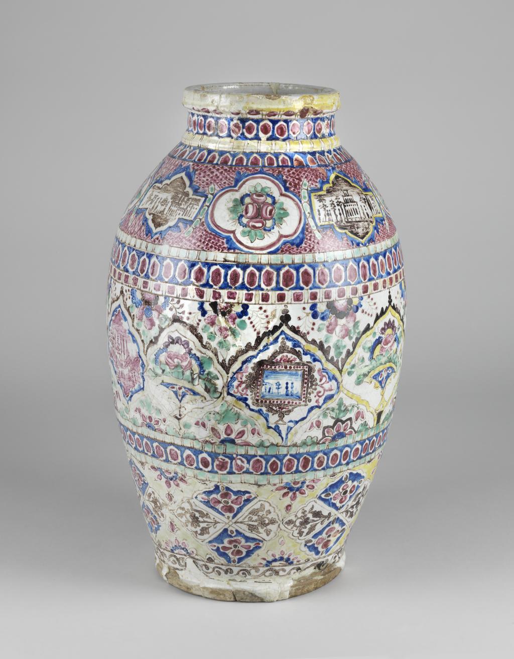 An image of Jar. Unknown potter, Iran. Islamic pottery. Shape: inverted pear-shaped body, ascending onto a collared neck and indented rectangular rim, sits on a flat disc base that protrudes from the lower body. Exterior: on the body three decorative friezes incorporate medallions painted with various scenes. On the upper register quatre foils with polychrome floral sprays and lozenges with square ends containing brown buildings flanked by trees, all painted on a red cross-hatched ground. The central frieze incorporates lobbed diamonds containing vases of polychrome flowers or landscape scenes, some of which are framed, in pink or blue. The spandrels between these medallions contain floral sprays. On the lowest resister lobbed diamonds contain rosettes reserved in blue of brown floral sprays. Dividing these friezes and on the neck, bands of circles, lozenges or squares, with the red examples often defined by a white outline and reserved in blue. The rim is partially covered with yellow and just above the base a band of brown scrolling vegetation is painted. Glaze runs over the lower body and foot ring unevenly. Interior: a green glaze coats the body, running over onto the white glaze of the neck in one place. Fritware, wheel thrown, coated in a white glaze painted with red, yellow, blue, green and brown enamels. Height, whole, 44.5 cm, width, whole, 26.5 cm, diameter, rim, 13.5 cm, diameter, base, 17.5 cm, weight, whole, 6190 g, circa 1800-circa 1899. Qajar period.