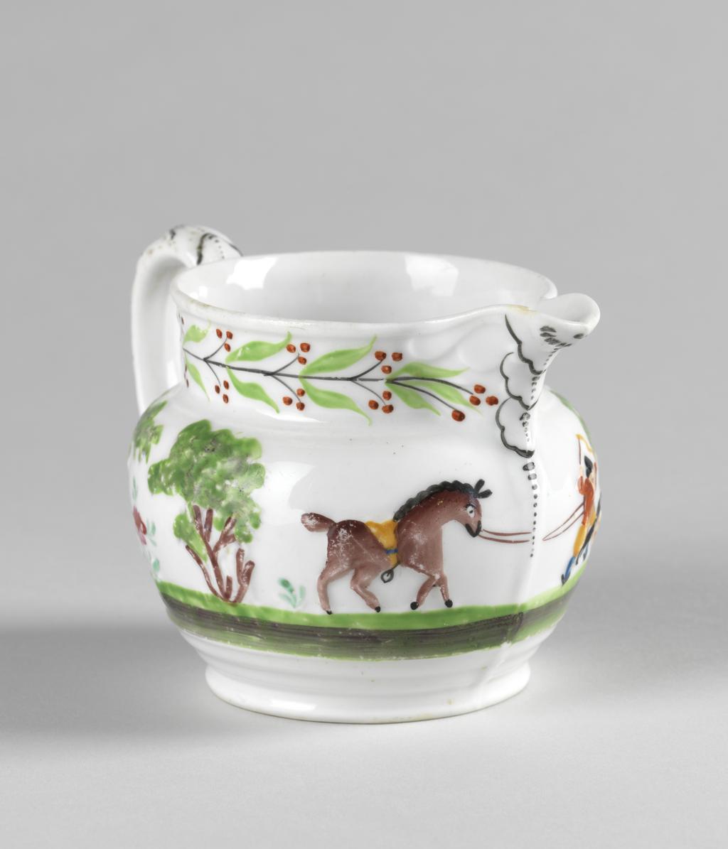 An image of Jug.  New Hall Porcelain Factory, Staffordshire, New Hall. With a hunting scene and a leaf and berry border painted in polychrome enamels. The bulbous jug stands on a low foot, and has a short cylindrical neck with a projecting lip. The strap handle is moulded with leaves in relief, and has a projecting finger rest near the lower end. On the sides, two men on horseback are galloping to the left towards a deer attacked by hounds beside a tree, and another man on foot who is brandishing a whip in one hand and holds the reigns of his horse in the other. On the other side is his horse trotting to the right, and behind it, two trees with a stylized flowering plant between them. Round the neck there is a continuous black stem bearing paired green leaves and paired black stalks with three red berries on each. The leaves on the back of the handle are outlined in black and have black dotted central vein. Bone china, moulded with decoration in relief, painted overglaze in blue, green, yellow, red, brown and black enamels, height, whole, 8.5 cm, length, whole, 12.5 cm, circa 1818-1825.
