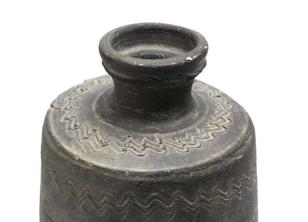 An image of Jar with cylindrical body and a short neck with everted rim. The body is heavy, dark grey and decorated with three combed wavy bands. The base is flat. Stoneware. Possibly Kaya Kingdom, 5th-6th century.