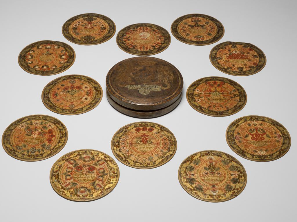 An image of Woodwork. Box of roundells. Box containing twelve trenchers. Wood, painted, gold decoration, height, box, 3.2 cm, diameter, box, 16.6 cm, diameter, roundels, 13.2 cm, circa 1600. Renaissance. Elizabeth I. English.
