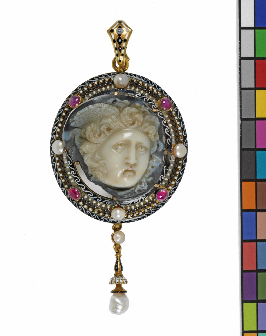 An image of Jewellery. Pendant. Unknown frame maker, London. Giuliano, Carlo, cameo maker (Italian jeweller in GBR, 1831-1895). Onyx cameo with white upper layer and dark lower layer, carved with a head of Medusa of Rondanini type. Shown frontally, the back left rough. Set by means of seven claws in an oval gold openwork frame enamelled black and white and set with four pearls and four cobochon pink gemstones. Suspended from the lower edge are a pearl, and an enamelled gold 'tassel' with a larger pearl at the end. At the top there is a ring and an enamelled gold loop for suspension. Height, whole, 8.2 cm, width, whole, 3.8 cm, height, cameo, 2.5 cm, width, cameo, 2.6 cm, depth, cameo, 0.9, cm, circa AD 100-200, cameo, mount late 19th century. Revivalism. Production Note: This pendant unites a second century Roman Imperial cameo of Medusa with a Renaissance Revival style mount, by Carlo Giuliano one of the leading jewellers who worked in both the Renaissance and Archeological Revival styles.