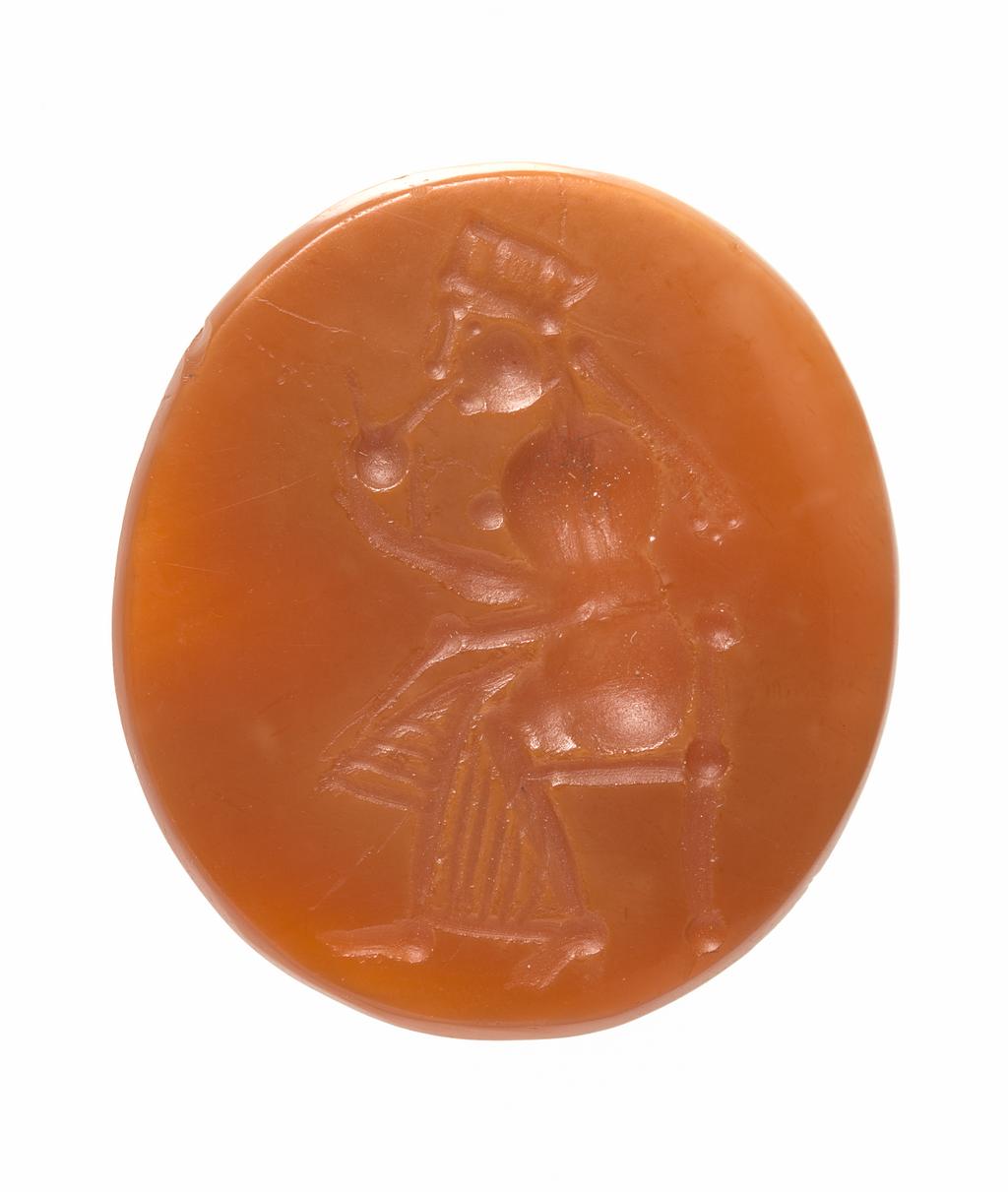 An image of Engraved gem impression. Intaglio. Ringstone. Production: Unknown maker, India, North-West Frontier. Seated woman, wearing chiton, head-dress and pigtails, holding round object - goddess Anahita? Intaglio cutting. Carnelian, height 23 mm, width 21 mm, depth 3 mm, circa 300-circa 250 B.C. Graeco Persian derivative. Alternative Number: gem catalogue number; O.38.1951.
