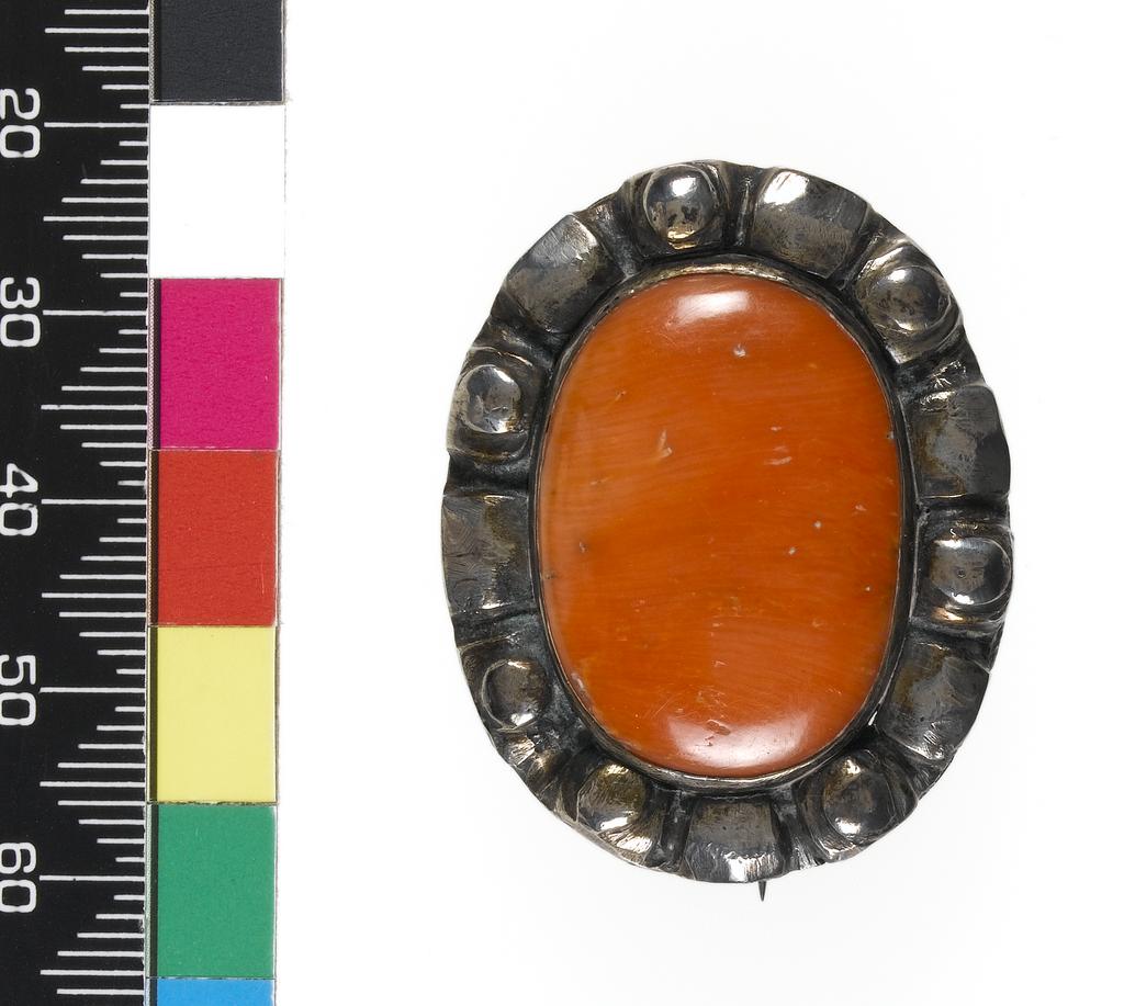 An image of Jewellery. Oval brooch with a pin fastening on the back. Stein, Leo probably (1872-1947). Silver set with coral, length (whole) 3.8 cm, width (whole) 3 cm, circa 1900. Notes: This brooch is the one worn by Gertrude Stein in the portrait by Picasso of 1906. Colmar, Paris.