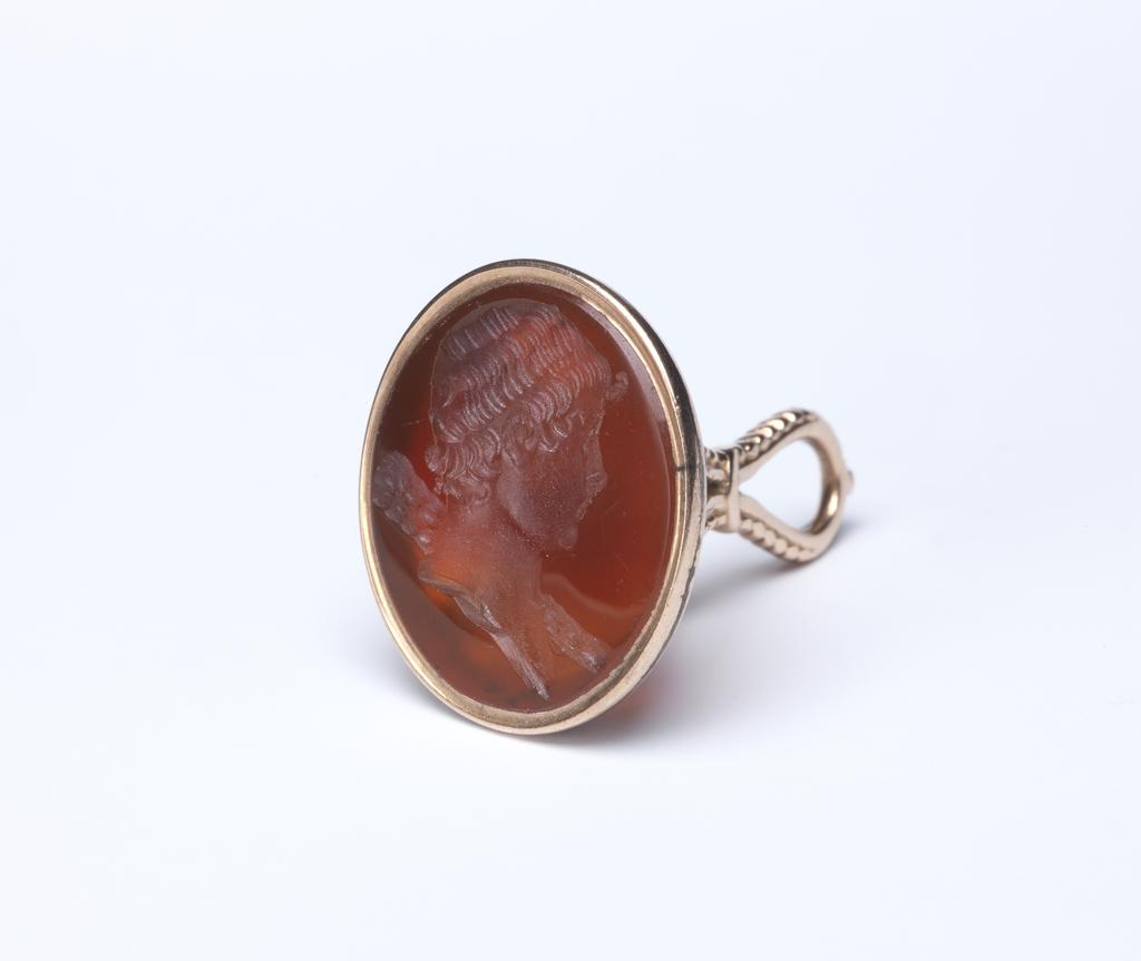 An image of Seal/Intaglio. Head of Hercules to right, with club over left shoulder. Intaglio red carnelian oval in a gold mount, height 18 mm, width 16 mm, late 18th Century. CG 714.