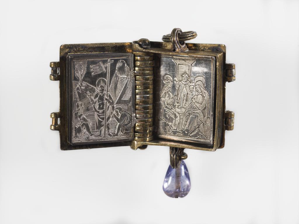 An image of Pendant Book. Jewellery/Pendant. Silver-gilt, with leaves made of silver and engraved with scenes from the Passion. Perhaps for attaching to a rosary, with pendant amethyst. Scenes: Annunciation, Nativity, Last Supper, Agony in the Garden, Kiss of Judas, Christ before Pilate, Scourying of Christ, The Mocking of Christ, Christ Carrying the Cross, the Erection of the Cross, Christ being Nailed to the Cross, the Crucifixion Deposition, Entombment, Resurrection, Christ Child Enthroned, a Pope and a female Saint. Silver-gilt, height, whole, 6.0 cm, width, whole, 2.8 cm, circa 1500- circa 1700. German.