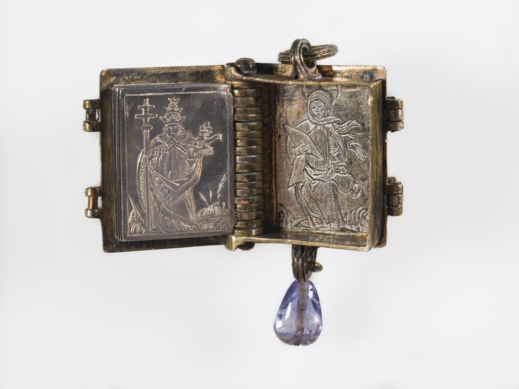 An image of Pendant Book. Jewellery/Pendant. Silver-gilt, with leaves made of silver and engraved with scenes from the Passion. Perhaps for attaching to a rosary, with pendant amethyst. Scenes: Annunciation, Nativity, Last Supper, Agony in the Garden, Kiss of Judas, Christ before Pilate, Scourying of Christ, The Mocking of Christ, Christ Carrying the Cross, the Erection of the Cross, Christ being Nailed to the Cross, the Crucifixion Deposition, Entombment, Resurrection, Christ Child Enthroned, a Pope and a female Saint. Silver-gilt, height, whole, 6.0 cm, width, whole, 2.8 cm, circa 1500- circa 1700. German.