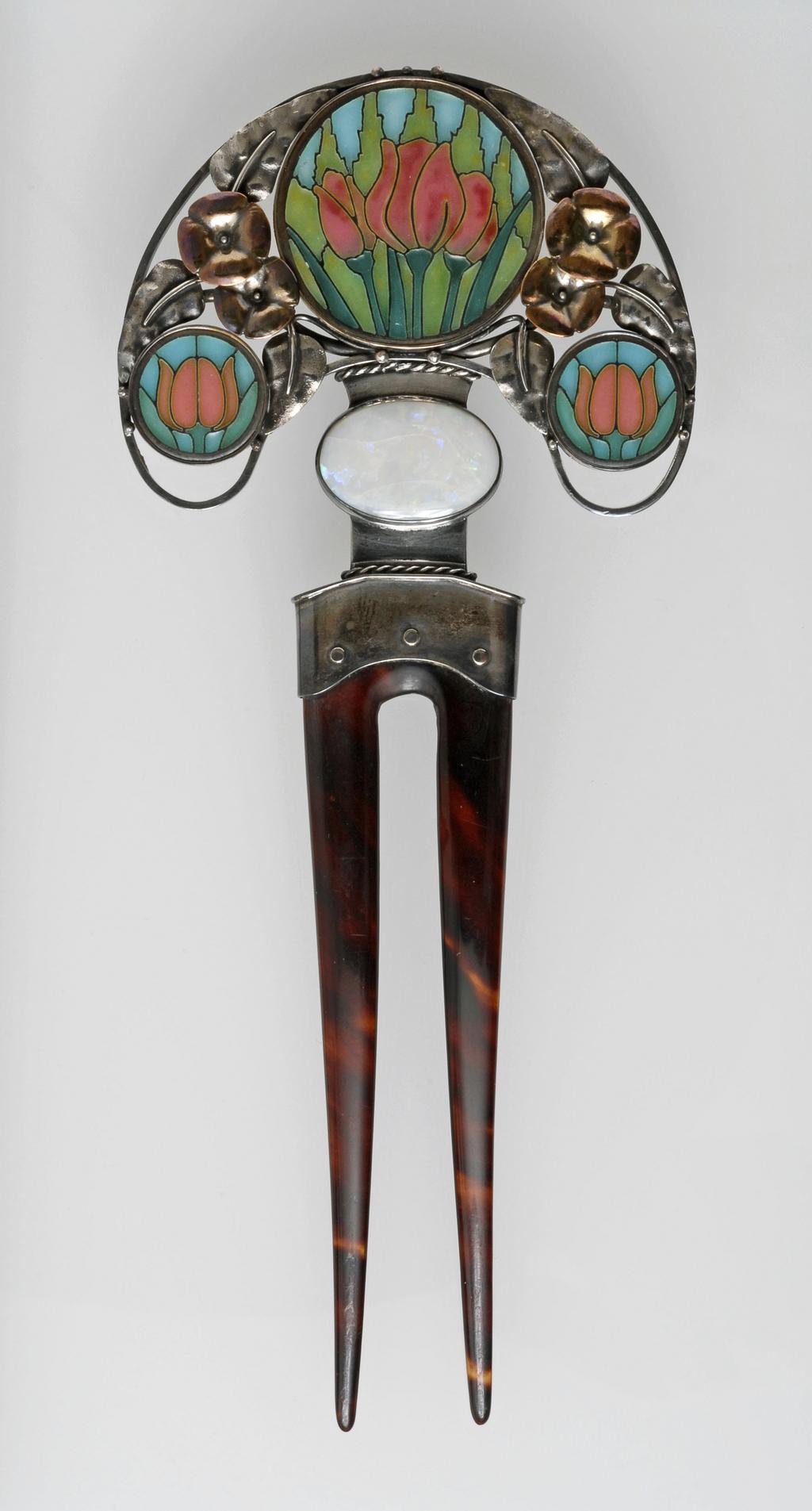 An image of Hair ornament. Wilson, Henry (British, 1864-1934), attributed. Silver and gold, inset with turquoise, pink, pale and dark green plique-à-jour roundels of tulips and an oval opal, mounted on a tortoiseshell two-pronged hair pin. 1900-1905. English. Art Nouveau. Acquisition Credit: Given by Mrs J. Hull Grundy.