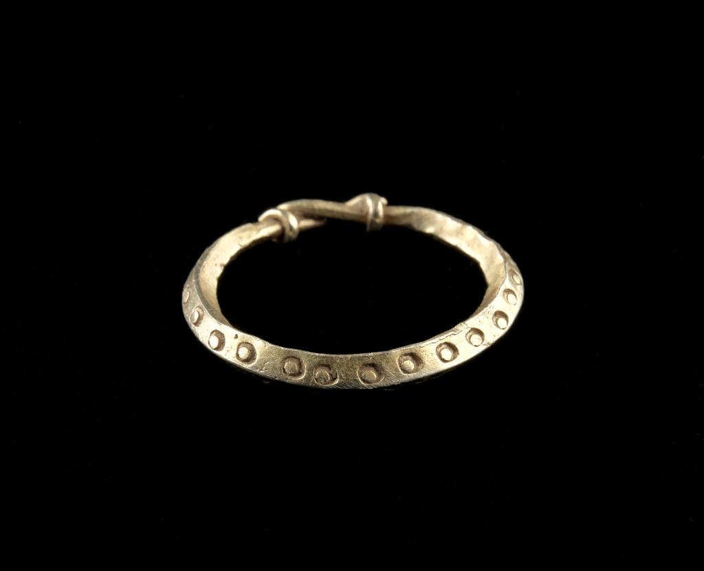 An image of Jewellery/Finger Ring. Lozenge-shaped section rod, drawn into wires which overlap and are wound round each other; both outer faces are decorated with punched circles. Gold (35-50%), silver (55-60%) and copper. 9th-10th Century. Viking Period.