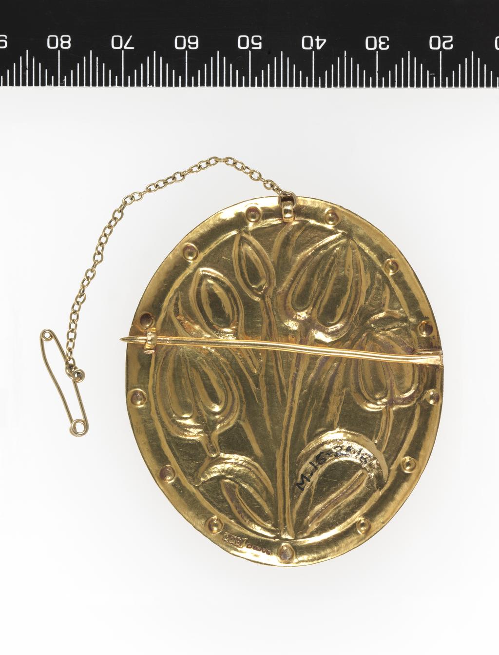 An image of Jewellery/Brooch. Ashbee, Charles Robert, designer (British, 1863-1942). Hart, Henry, designer (British). Hart, David, silversmith (British). 22 carat gold, oval with embossed tulips and border of thirteen small bosses. In associated red leather case, initialled and dated in gold 'C.L.C./1906' on the top of the lid. (A). H.O. Hart's invoice for the brooch (B). Hart address card used as a gift card addressed to Mr Ward's mother in 1979 (C). Gold brooch, embossed, leather case. Designed 1906, made 1979. Arts and Crafts. 