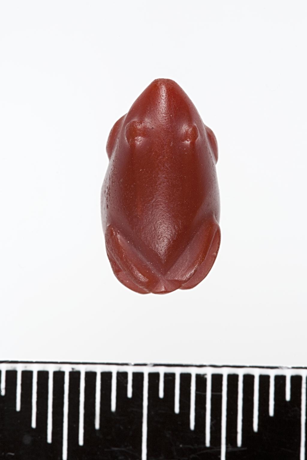 An image of Jewellery/ Amulet. Frog Amulet. Production Place: Egypt. Find Spot: Sedment, Egypt. Carnelian, polished, height 1.8 cm, 1479-1425 B.C. Eighteenth Dynasty. New Kingdom.