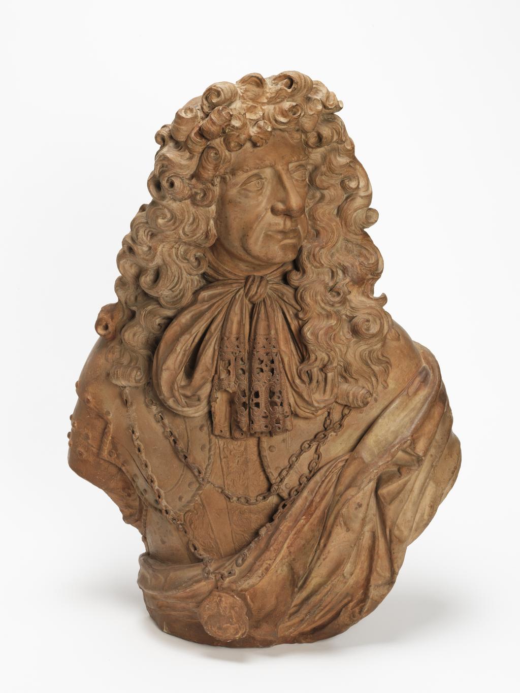 An image of Sculpture/Bust. King Charles II (1630-1685). Bushnell, John (British, c.1606-1701). Terracotta, height 78.5 cm, circa 1678. Baroque. The King's head is turned to the front, facing and looking half-right. He has a small moustache and a long, curling periwig, falling over both shoulders. He wears armour, with a double chain holding the Garter medallion of St George, a lace trimmed cravat tied in a bow, and a cloak draped over his left shoulder.